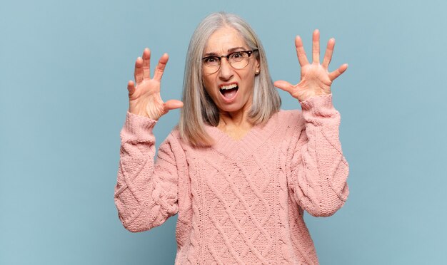 Femme d'âge moyen criant avec les mains en l'air, se sentant furieuse, frustrée, stressée et bouleversée