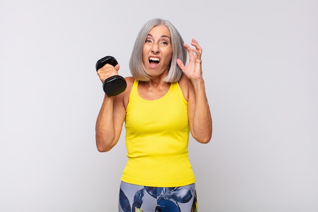 Femme d'âge moyen crier avec les mains en l'air, se sentir furieux