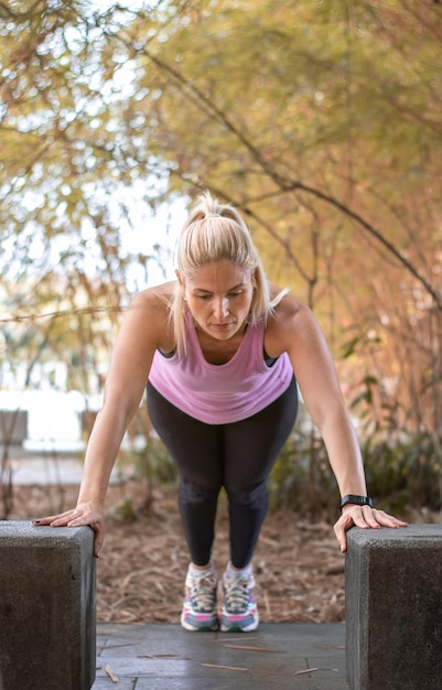 Femme d'âge moyen Crossfit faisant des pompes sur des bancs de parc