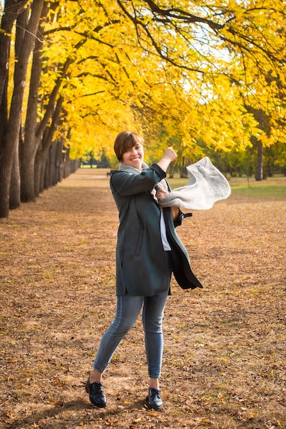 Femme d'âge moyen dans un foulard, se promène dans le parc de l'automne.