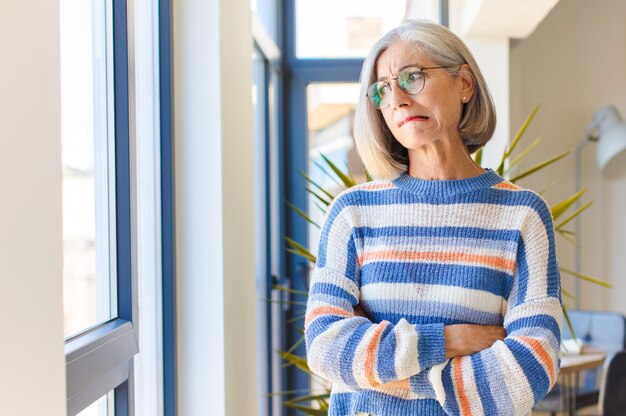 Femme d'âge moyen doutant ou pensant, mordant la lèvre et se sentant anxieuse et nerveuse, à la recherche de copier l'espace sur le côté