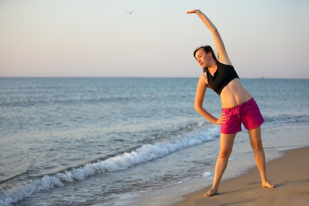 Une femme d'âge moyen fait des exercices au bord de la mer
