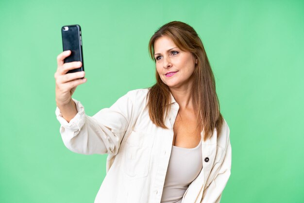 Femme d'âge moyen sur fond isolé faisant un selfie