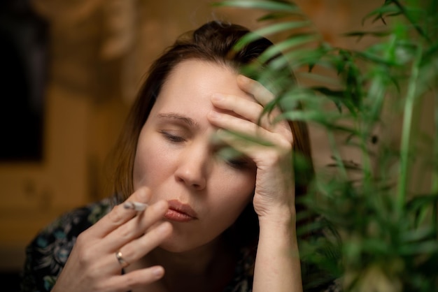 Une femme d'âge moyen fume Entouré de plantes vertes Concept de relaxation d'épuisement de fatigue