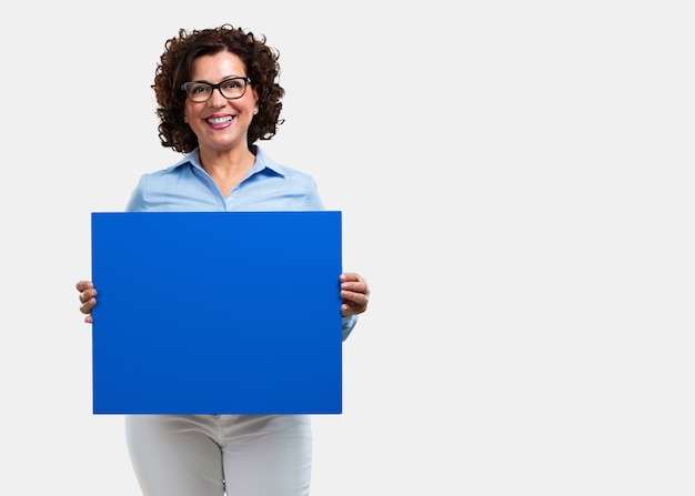 Femme d&#39;âge moyen gaie et motivée, montrant une affiche vide où vous pouvez montrer un