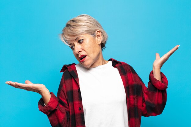 Photo femme d'âge moyen haussant les épaules avec une expression stupide, folle, confuse, perplexe, se sentant agacée et désemparée