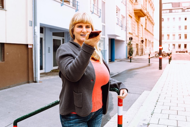 Femme d'âge moyen heureuse mature, 40 ans, aux longs cheveux blonds, souriante, portant des jeans et une veste tricotée