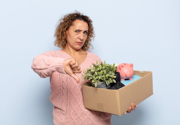 Femme d'âge moyen hispanique se sentant en colère, en colère, ennuyée, déçue ou mécontente, montrant les pouces vers le bas avec un regard sérieux