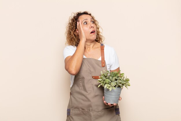 Femme d'âge moyen hispanique se sentir heureux, excité et surpris, regardant sur le côté avec les deux mains sur le visage