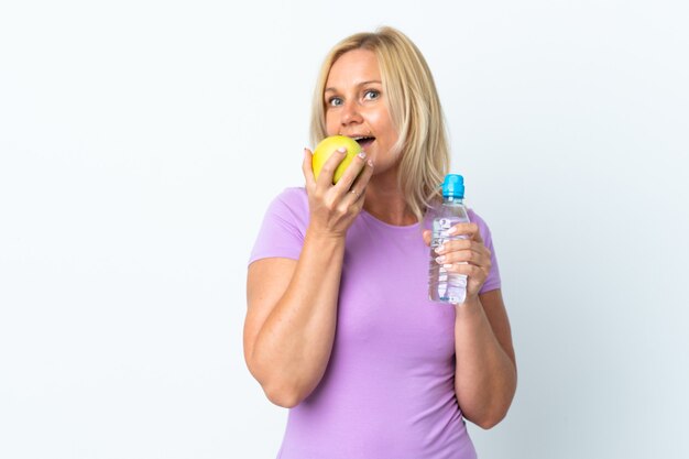 Femme d'âge moyen isolée sur blanc avec une pomme et avec une bouteille d'eau