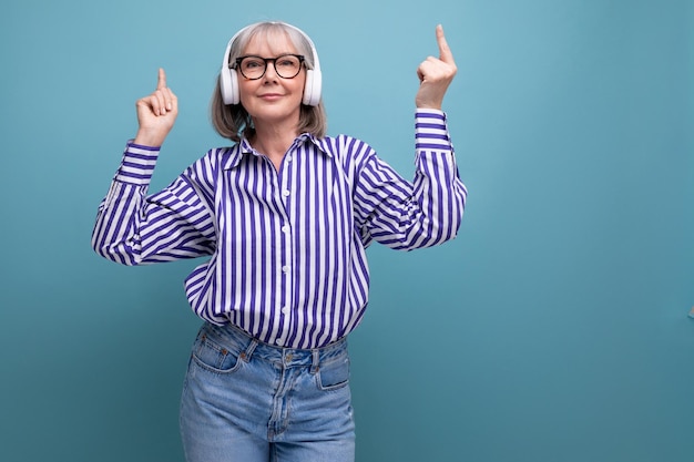 Femme d'âge moyen joyeuse et lumineuse aux cheveux gris avec un casque sans fil sur un studio lumineux