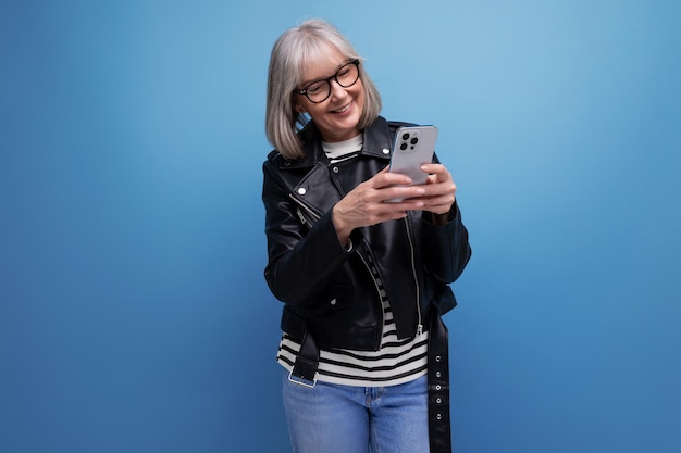 Femme d'âge moyen moderne énergique aux cheveux gris discutant sur internet à l'aide d'un smartphone sur
