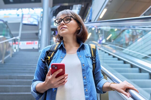 Femme d'âge moyen en montant les escaliers près de l'escalator dans la construction d'une gare moderne