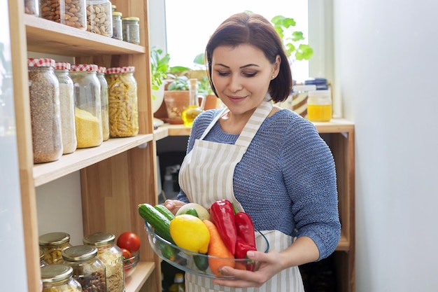 Femme d'âge moyen avec de la nourriture dans le garde-manger de la cuisine