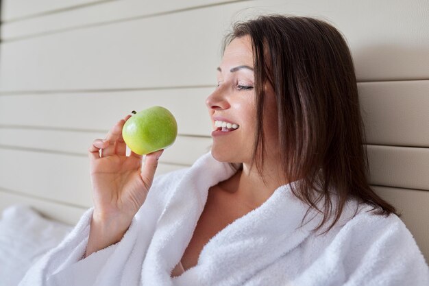 Femme d'âge moyen en peignoir blanc avec pomme verte au lit