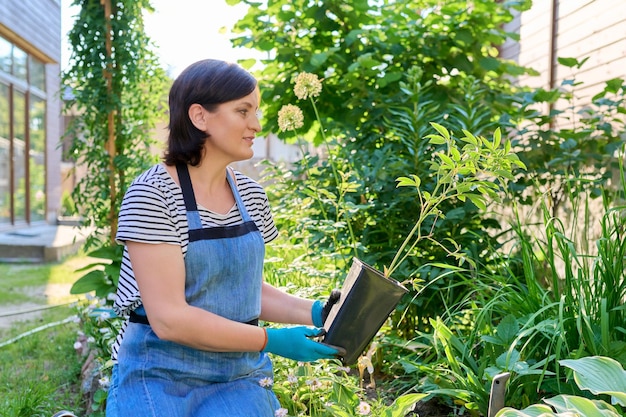 Femme d'âge moyen avec une plante de pivoine dans un pot pour la plantation dans un jardin de printemps