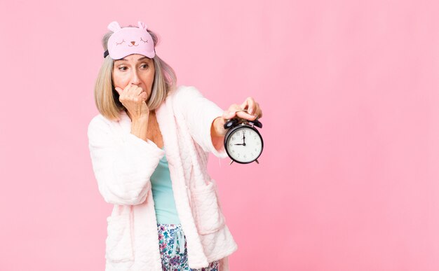 Femme d'âge moyen portant un costume de nuit avec un réveil