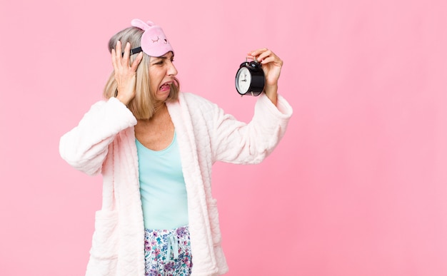 Femme d'âge moyen portant un costume de nuit avec un réveil