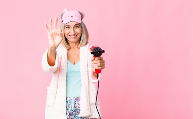 Femme d'âge moyen portant un costume de nuit avec un sèche-cheveux