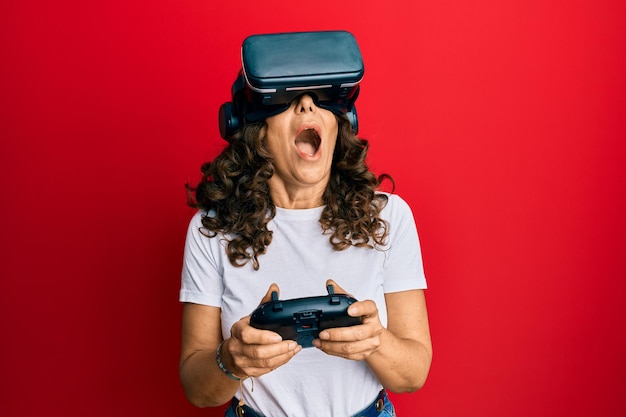 Femme d'âge moyen portant des lunettes de réalité virtuelle jouant à des jeux vidéo 3D regardant une expérience excitée de simulation futuriste