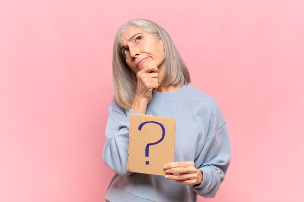 Femme d'âge moyen posant avec panneau de point d'interrogation