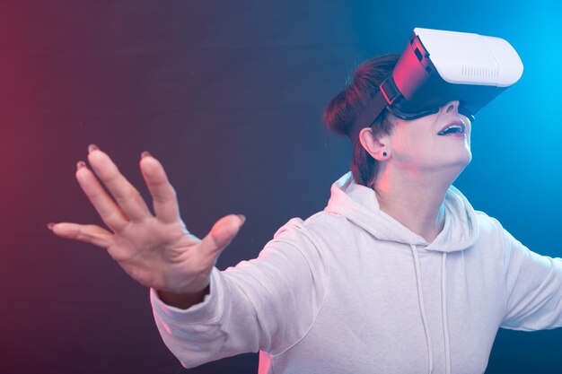 Femme d'âge moyen en pull regarde un nouveau film avec des lunettes de réalité virtuelle