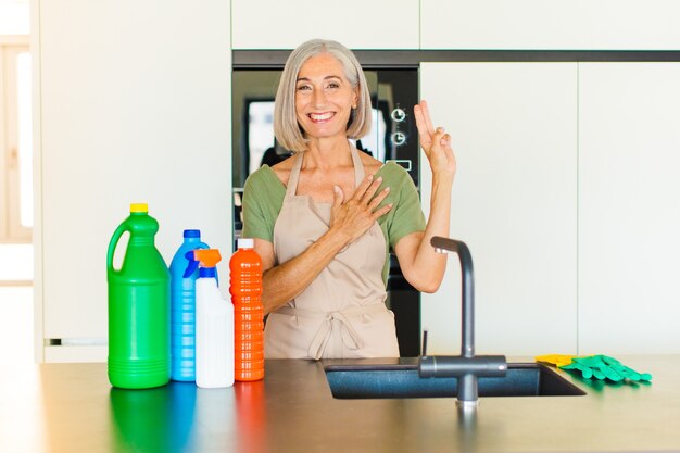 Femme d'âge moyen à la recherche de bonheur, confiant et digne de confiance, souriant et montrant le signe de la victoire, avec une attitude positive