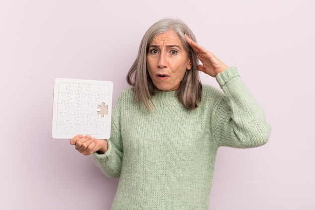 Femme d'âge moyen à la recherche de concept de défi de puzzle heureux étonné et surpris