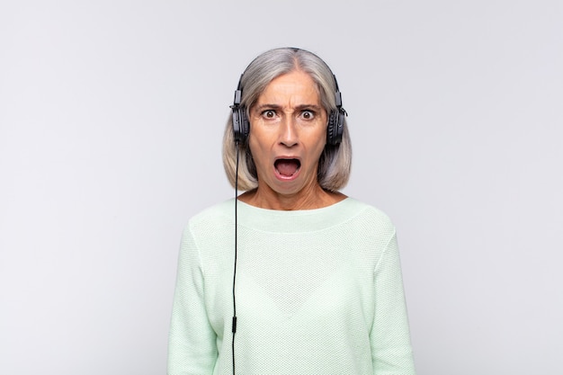 Femme d'âge moyen à la recherche très choquée ou surprise, regardant la bouche ouverte en disant wow. concept de musique