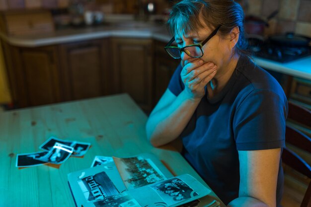 Femme d'âge moyen regardant l'album photo de famille Souvenirs de tristesse nostalgie au concept d'âge moyen