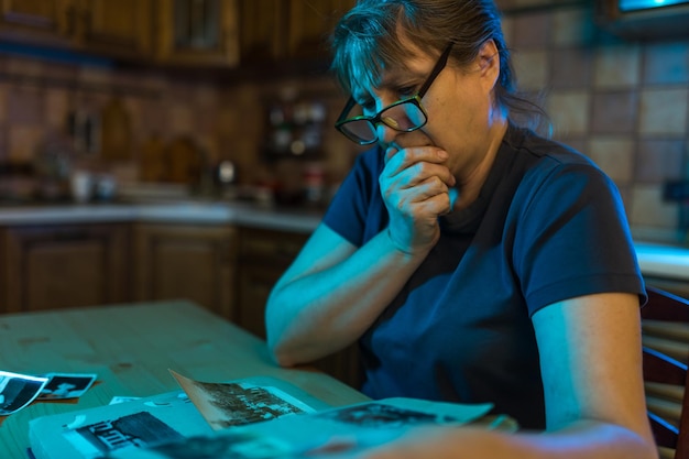 Femme d'âge moyen regardant l'album photo de famille Souvenirs de tristesse nostalgie au concept d'âge moyen