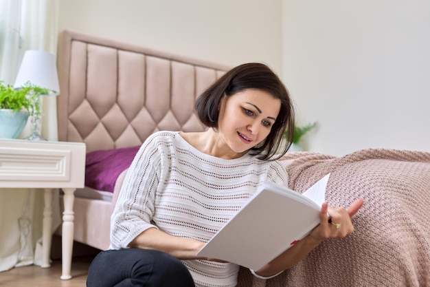 Femme d'âge moyen se détendre à la maison en lisant un livre