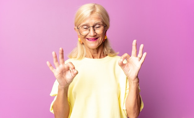 Femme d'âge moyen se sentant choquée, étonnée et surprise, montrant son approbation faisant signe d'accord avec les deux mains