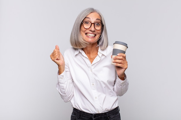 femme d'âge moyen se sentant choquée, excitée et heureuse, riant et célébrant le succès, disant wow! concept de café