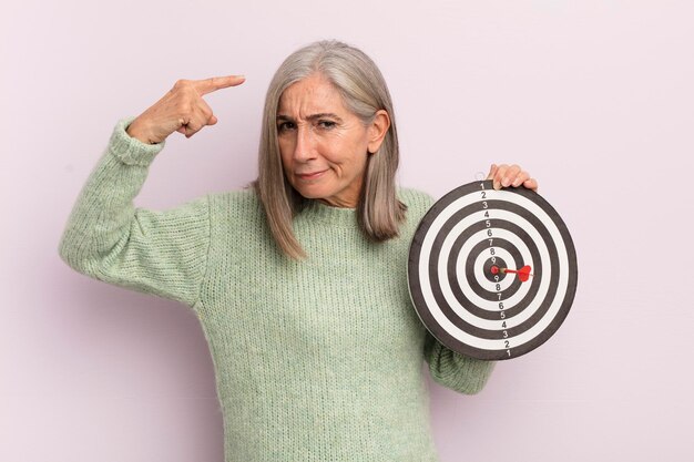 Photo femme d'âge moyen se sentant confuse et perplexe montrant que vous êtes un concept de cible de fléchettes fou