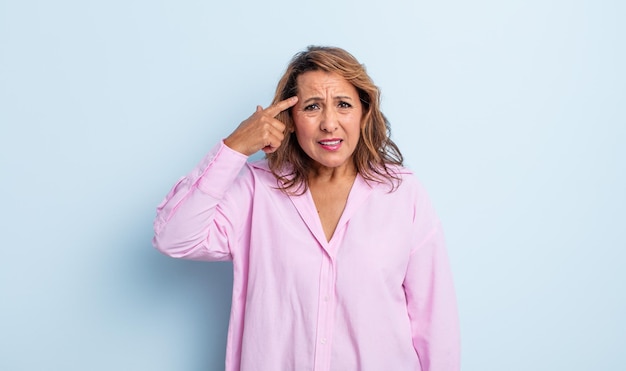 Femme d'âge moyen se sentant confuse et perplexe, montrant que vous êtes fou, fou ou fou