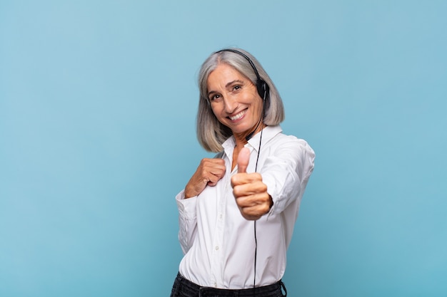 Femme d'âge moyen se sentant fière, insouciante, confiante et heureuse, souriant positivement avec les pouces vers le haut. concept de télévendeur