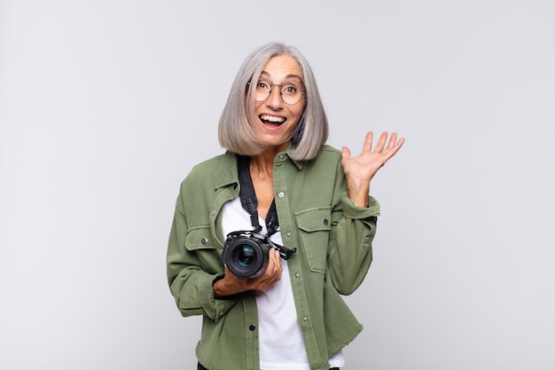 Femme d'âge moyen se sentant heureuse, excitée, surprise ou choquée, souriante et étonnée de quelque chose d'incroyable. concept de photographe