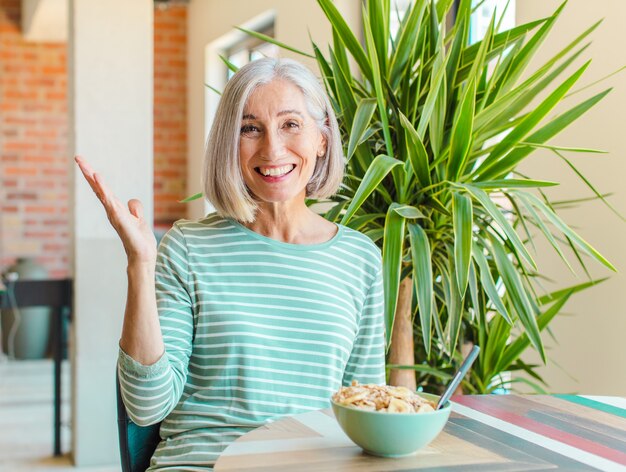 Femme d'âge moyen se sentant heureuse, surprise et joyeuse, souriant avec une attitude positive, réalisant une solution ou une idée