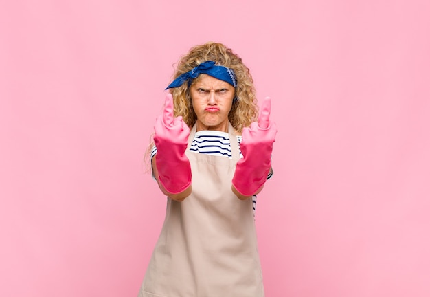 Femme d'âge moyen se sentant provocante, agressive et obscène, retournant le majeur, avec un concept de femme de ménage d'attitude rebelle