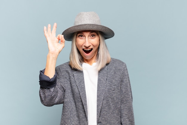 Femme d'âge moyen se sentant réussie et satisfaite, souriante avec la bouche grande ouverte