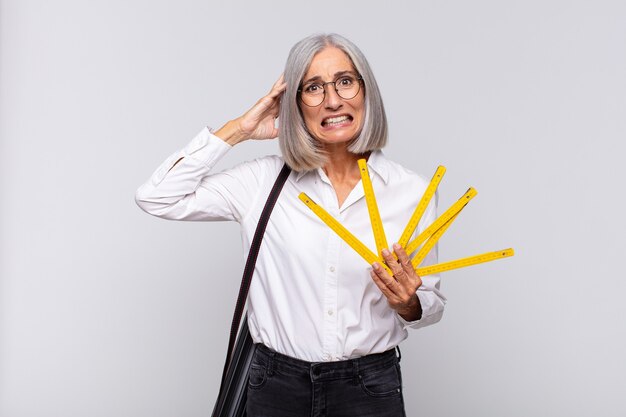 Femme d'âge moyen se sentant stressée, inquiète, anxieuse ou effrayée, les mains sur la tête, paniquant à l'erreur. concept d'architecte