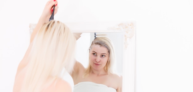 Une femme d'âge moyen se teint les cheveux à la maison, à l'intérieur