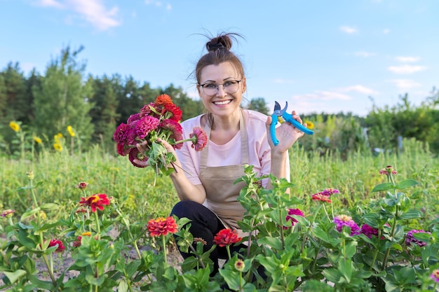 Femme d'âge moyen avec un sécateur coupant un bouquet de fleurs de zinnia