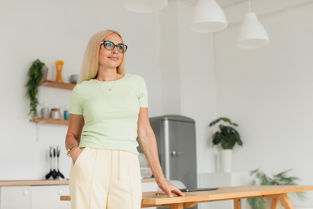 Femme d'âge moyen séduisante moderne posant dans la cuisine à la maison