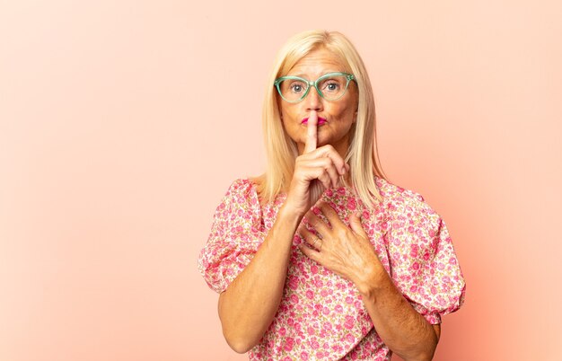 Femme d'âge moyen à la sérieuse et mécontente avec les deux doigts croisés à l'avant dans le rejet, demandant le silence