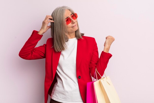 Femme d'âge moyen souriant joyeusement et rêvassant ou doutant du concept de shopping