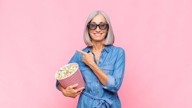 Femme d'âge moyen souriant joyeusement, se sentant heureux et pointant