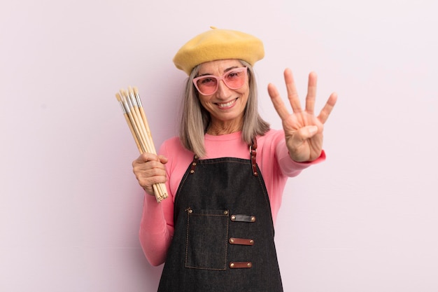 Femme d'âge moyen souriant et regardant amical montrant le concept de peintre d'artiste numéro quatre