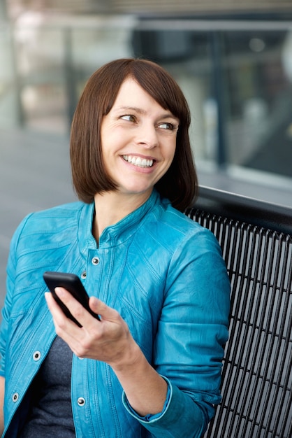 Femme d&#39;âge moyen souriant avec téléphone portable